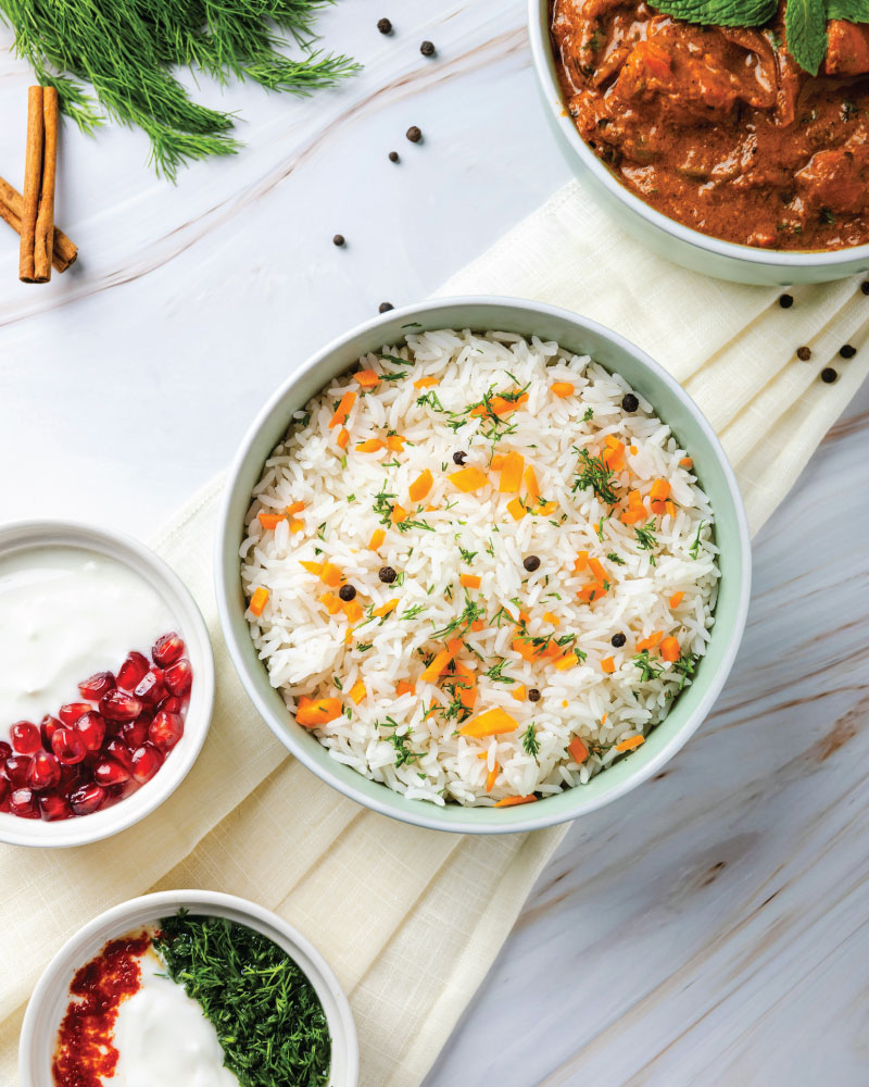 Traditional Indian meal with garnished basmati rice, curry and raita